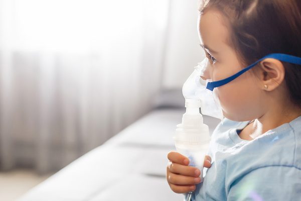 Little girl in a mask, treatments respiratory tract with a nebulizer at home